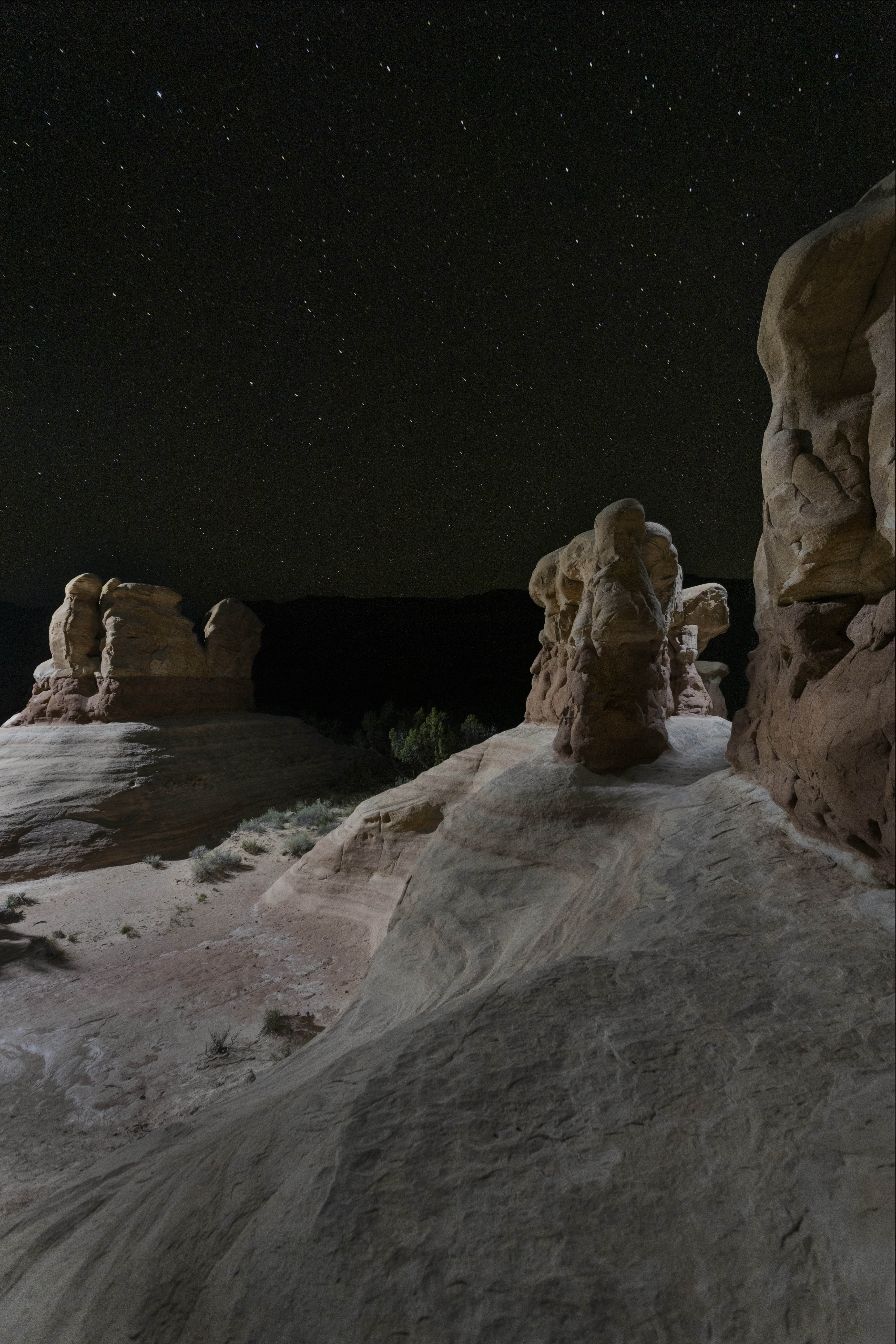 Vertical view of hoodoos on bare slickrock under a starry sky at night, Devils Garden, Grand Staircase-Escalante National Monument.