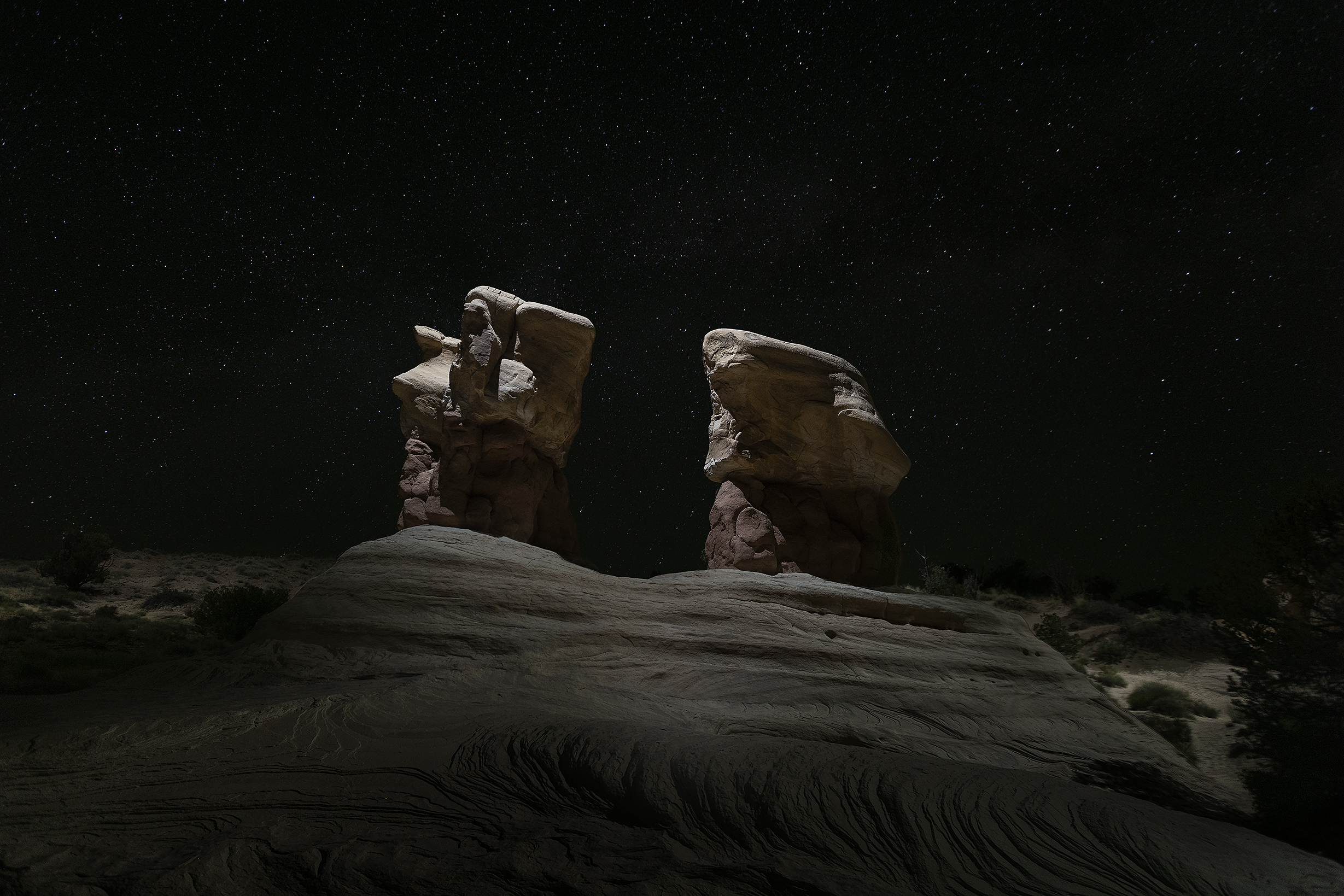 Two dark hoodoos nearly silhouetted against a dense field of stars at night, Devils Garden, Grand Staircase-Escalante National Monument.